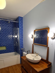 Load image into Gallery viewer, Bathroom with wooden vanity, sink, and blue tiled walls.